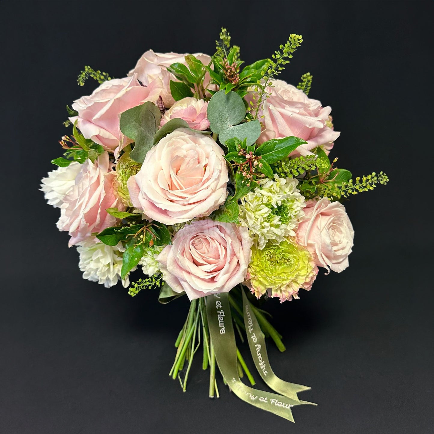 A vintage-inspired bridal bouquet with pastel pink roses, white hydrangeas, and greenery, accented with a satin ribbon.